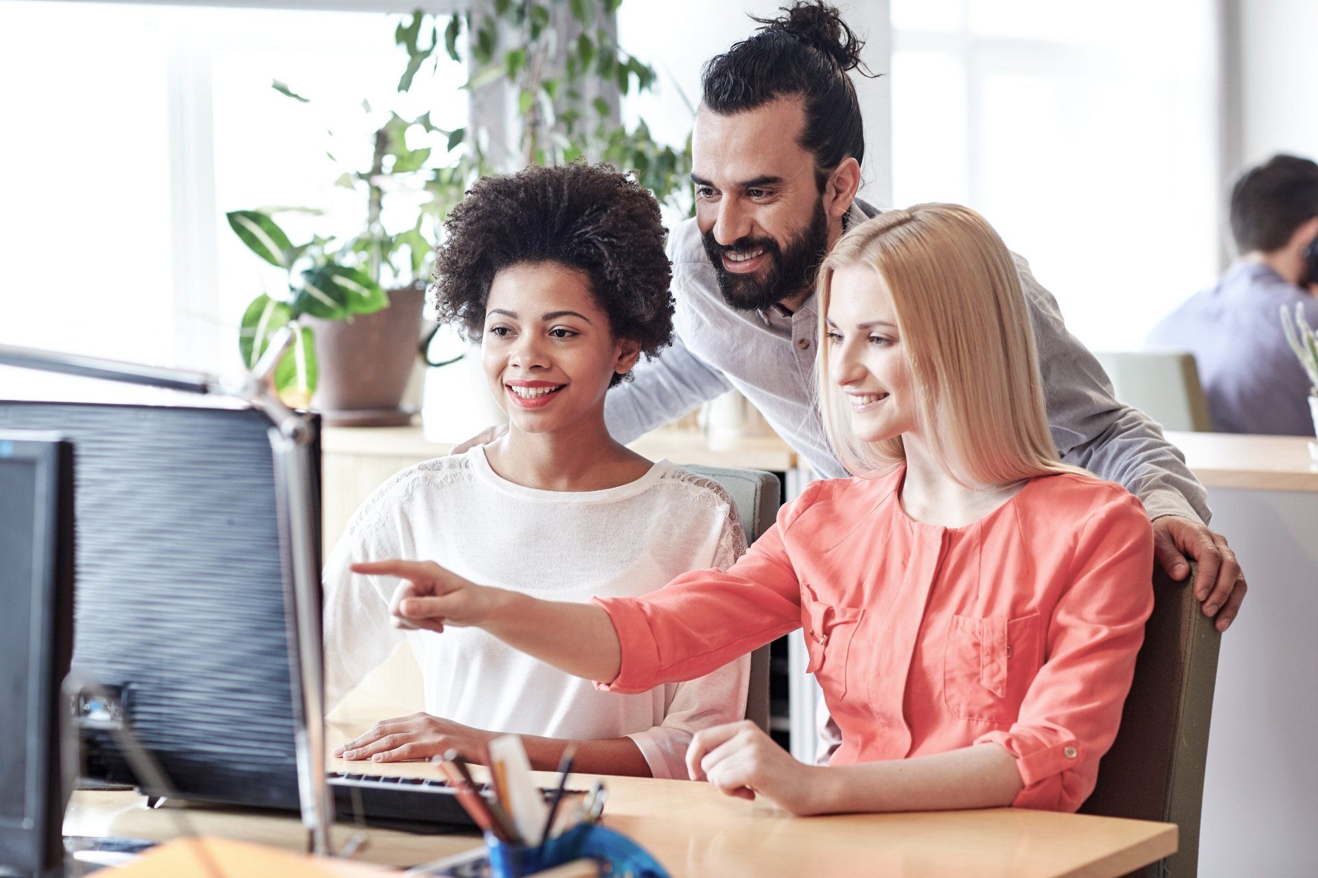 Three peoples are looking and smiling infront of the computer.